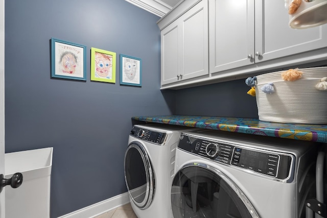 clothes washing area with washing machine and dryer, cabinet space, and baseboards