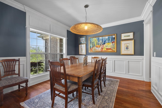 dining space featuring crown molding, a wainscoted wall, and a decorative wall