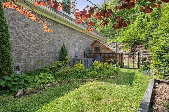 view of side of property with a gate, brick siding, fence, and a lawn
