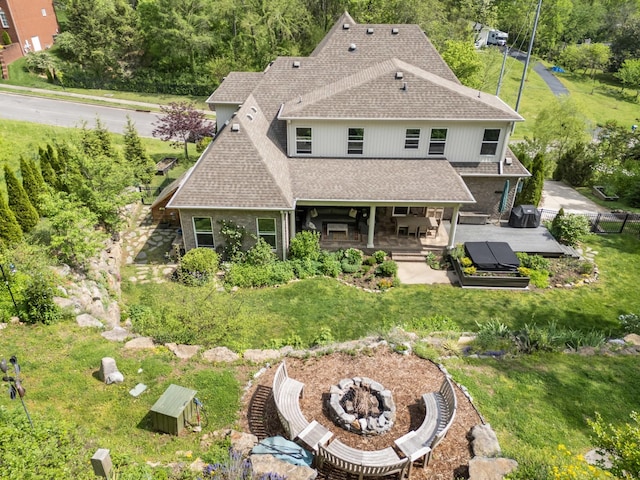 back of property featuring a deck, a yard, a fire pit, fence, and roof with shingles
