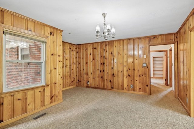 909 Hillsboro Rd, Franklin, TN 37064 - empty room with wooden walls, an inviting chandelier, visible vents, and carpet floors