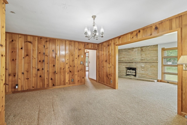 909 Hillsboro Rd, Franklin, TN 37064 - carpeted empty room featuring a stone fireplace, wood walls, baseboards, and a notable chandelier