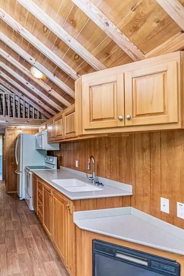 5755 Railroad St, Williston, TN 38076 - kitchen featuring white appliances, wood ceiling, wooden walls, wood finished floors, and a sink
