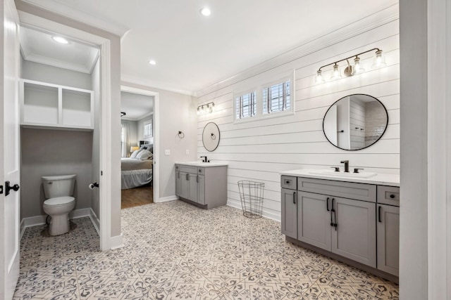 ensuite bathroom featuring toilet, crown molding, two vanities, recessed lighting, and baseboards