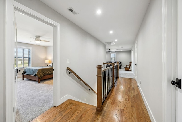 hall with an upstairs landing, wood finished floors, recessed lighting, baseboards, and carpet floors