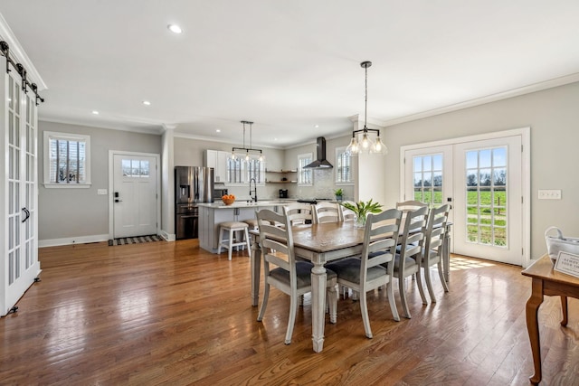 dining area featuring french doors, wood finished floors, healthy amount of natural light, crown molding, and recessed lighting