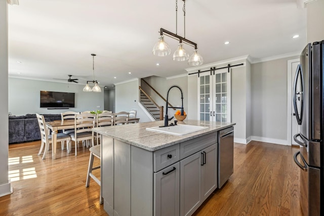 kitchen with a sink, stainless steel appliances, gray cabinets, a ceiling fan, and ornamental molding