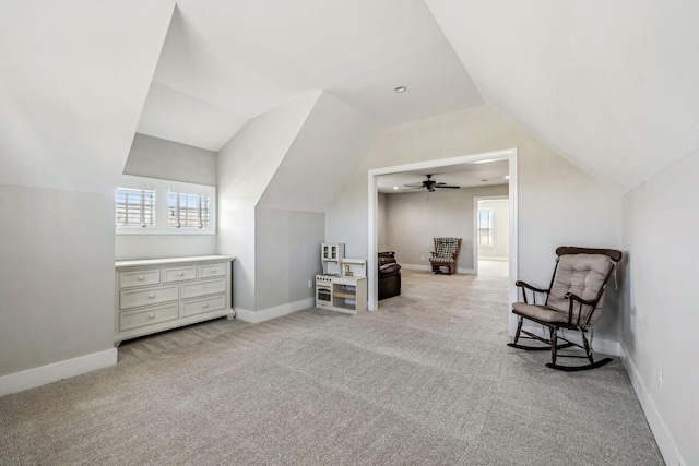 living area featuring vaulted ceiling, light carpet, and baseboards