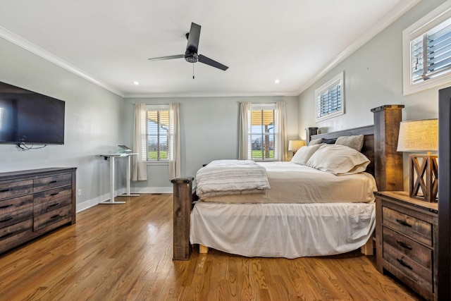 bedroom with crown molding, wood finished floors, multiple windows, baseboards, and a ceiling fan