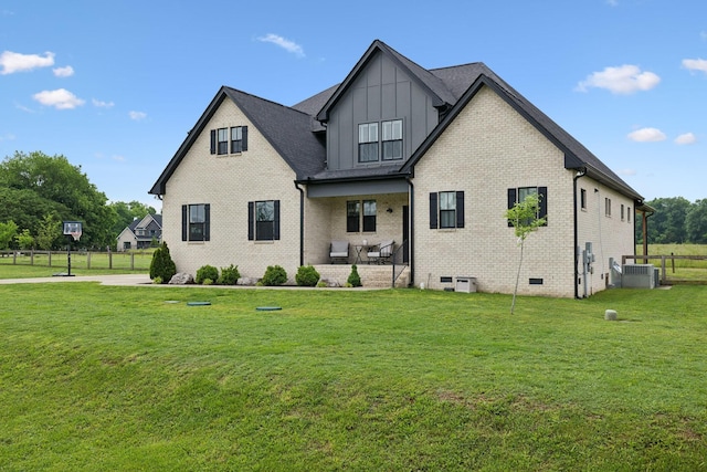 view of front of property with board and batten siding, a front yard, brick siding, and central AC