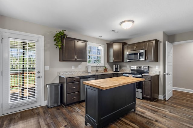 kitchen with dark brown cabinets, stainless steel appliances, butcher block countertops, and a sink