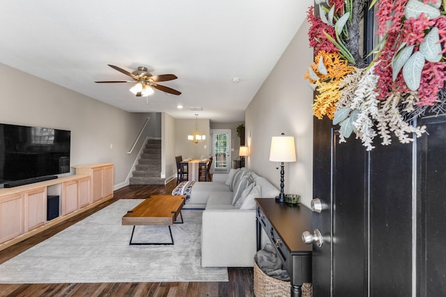 living area featuring baseboards, wood finished floors, stairs, and ceiling fan