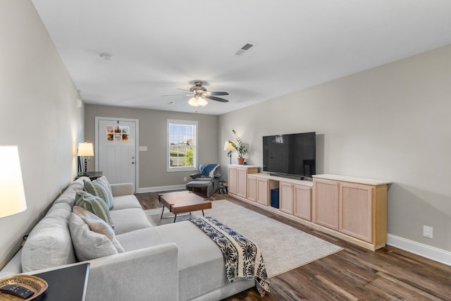 living room featuring baseboards, a ceiling fan, visible vents, and dark wood-style flooring