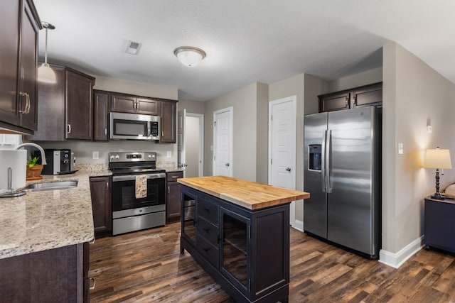 kitchen with dark wood-style floors, wooden counters, dark brown cabinets, a sink, and appliances with stainless steel finishes
