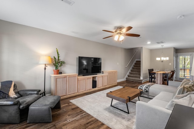 living area with stairs, ceiling fan with notable chandelier, baseboards, dark wood-type flooring, and visible vents