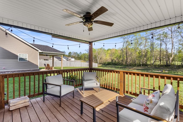 wooden terrace with an outdoor living space, ceiling fan, a lawn, and fence