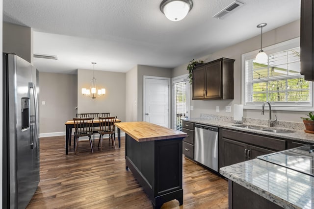 kitchen featuring butcher block countertops, a sink, an inviting chandelier, appliances with stainless steel finishes, and visible vents