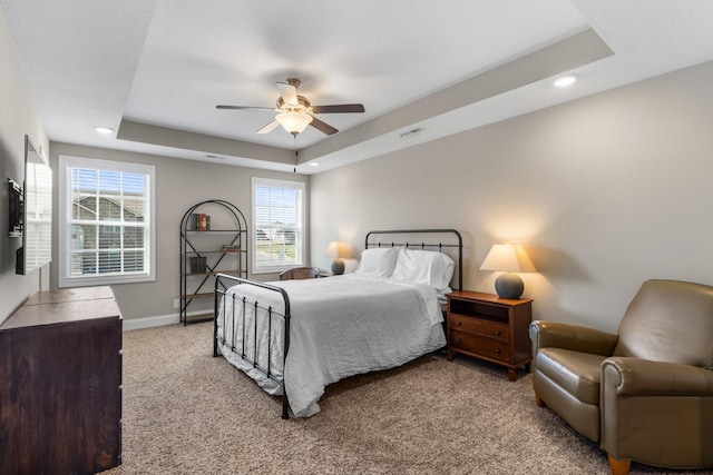 carpeted bedroom featuring recessed lighting, visible vents, ceiling fan, and a tray ceiling
