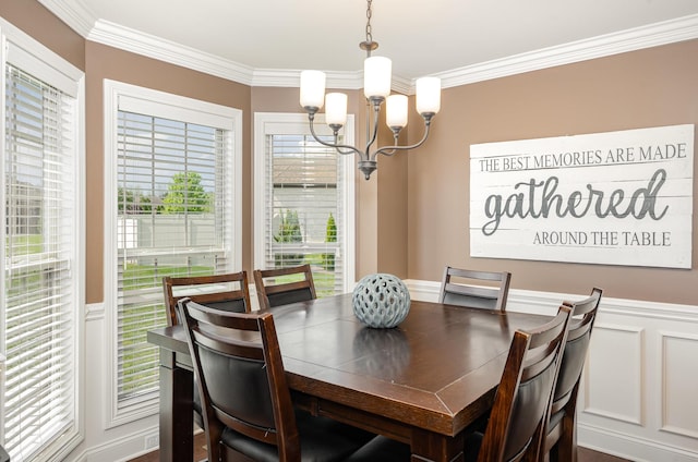 dining space featuring a chandelier, a decorative wall, ornamental molding, and wainscoting