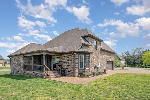 rear view of property with a shingled roof, aphalt driveway, a yard, and brick siding