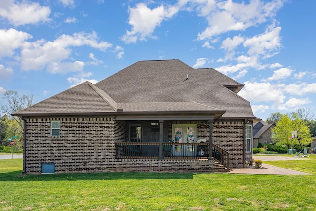 rear view of house with brick siding, a lawn, and a shingled roof