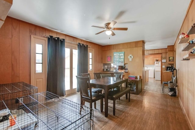 dining room with wood finished floors, a ceiling fan, and wood walls