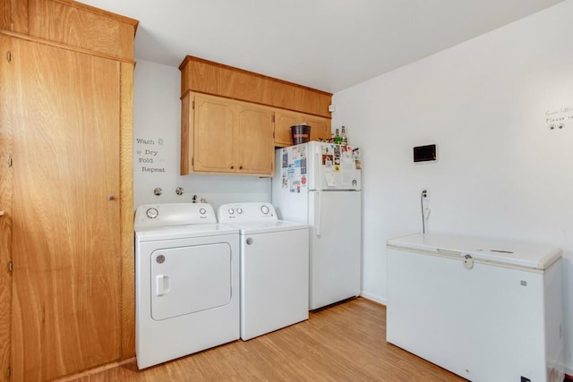 clothes washing area with cabinet space, light wood finished floors, and separate washer and dryer