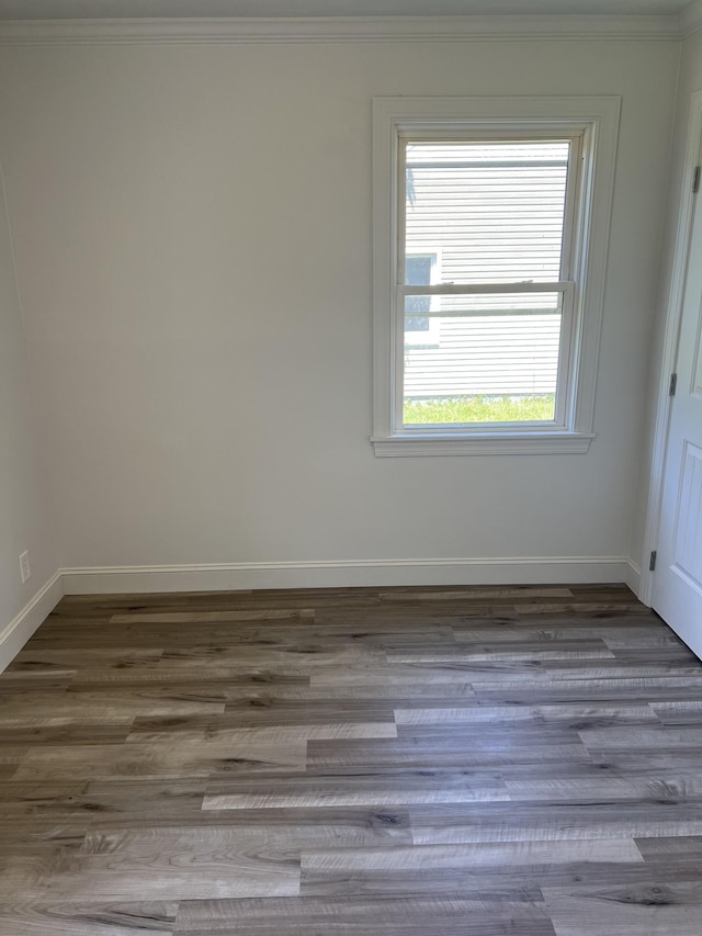 unfurnished room with wood finished floors, crown molding, and baseboards