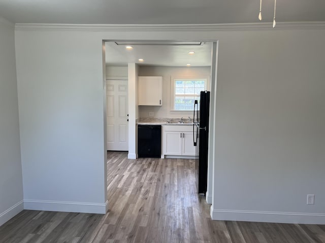 kitchen with light wood finished floors, baseboards, white cabinetry, crown molding, and black appliances
