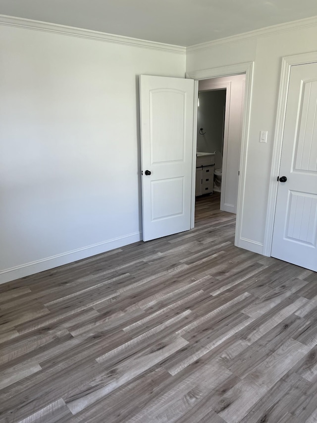 unfurnished bedroom featuring baseboards, wood finished floors, and crown molding