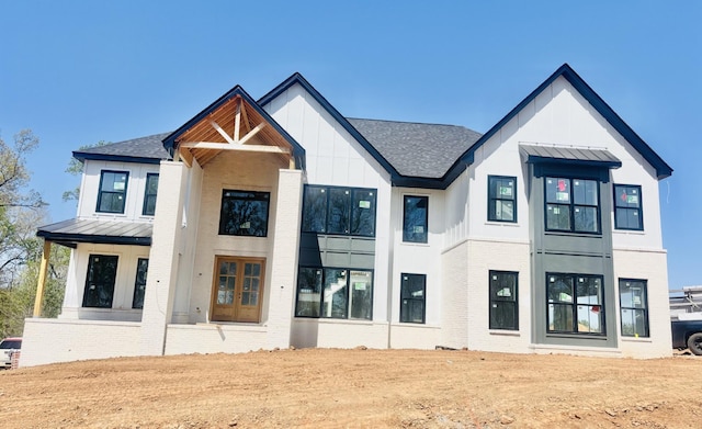 exterior space with a shingled roof, brick siding, board and batten siding, a standing seam roof, and metal roof