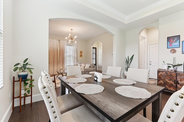 dining room with crown molding, wood finished floors, a chandelier, arched walkways, and baseboards