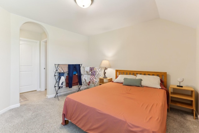 bedroom with arched walkways, carpet floors, lofted ceiling, and baseboards