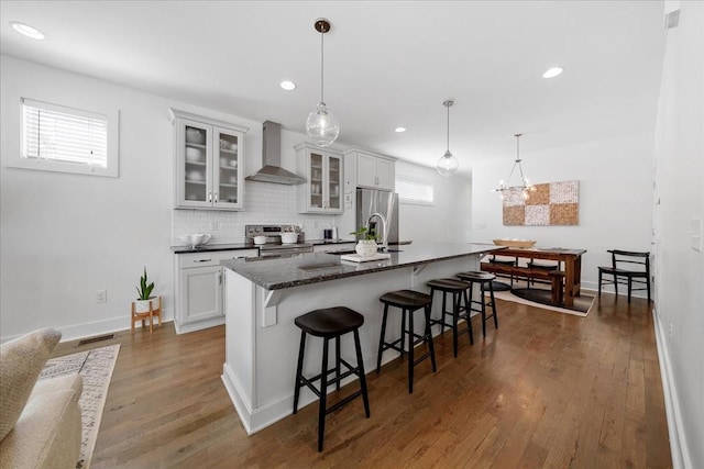 2123A 14th Ave N, Nashville, TN 37208 - kitchen featuring an island with sink, stainless steel appliances, a breakfast bar, a sink, and wall chimney exhaust hood