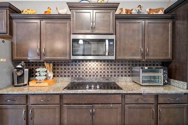 1438 Millet Dr, Clarksville, TN 37040 - kitchen with stainless steel microwave, dark brown cabinets, black electric stovetop, and backsplash