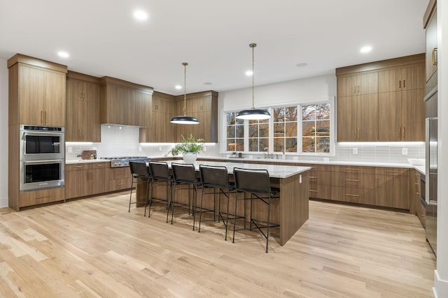 kitchen with brown cabinets, backsplash, appliances with stainless steel finishes, and a center island