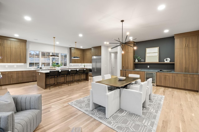 dining area with recessed lighting, light wood-style floors, beverage cooler, and a chandelier