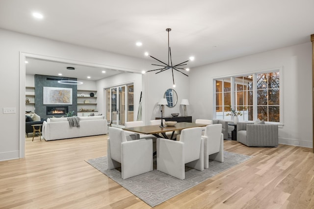 dining room featuring recessed lighting, light wood-style flooring, a fireplace, and a chandelier