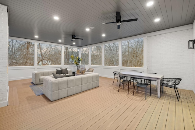 sunroom / solarium featuring a wooden deck, a ceiling fan, and outdoor dining space