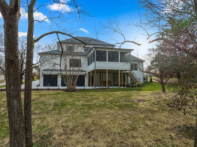 back of property featuring stairway, a yard, concrete driveway, a sunroom, and a garage