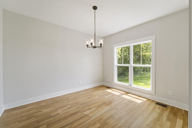 unfurnished room with baseboards, visible vents, a chandelier, and light wood finished floors