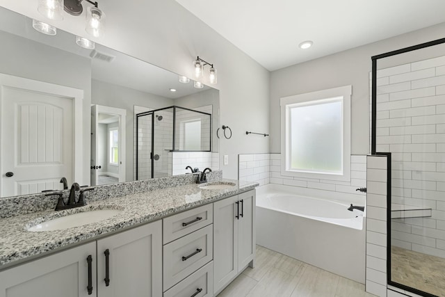 full bathroom featuring a shower stall, a garden tub, a sink, and visible vents