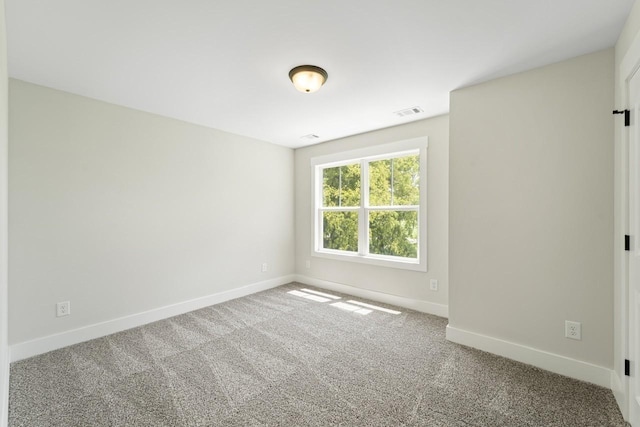 carpeted spare room with visible vents and baseboards