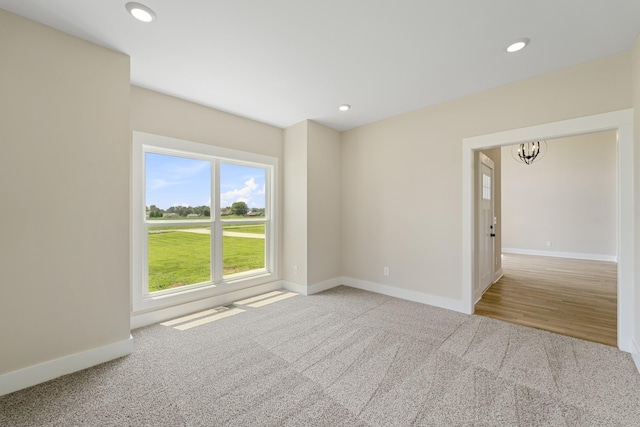 carpeted spare room featuring recessed lighting, baseboards, and a notable chandelier