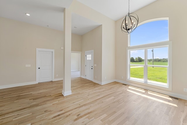unfurnished dining area with light wood-style floors, a high ceiling, and a healthy amount of sunlight