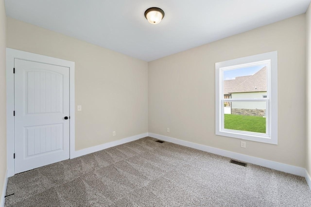 empty room with baseboards, visible vents, and carpet