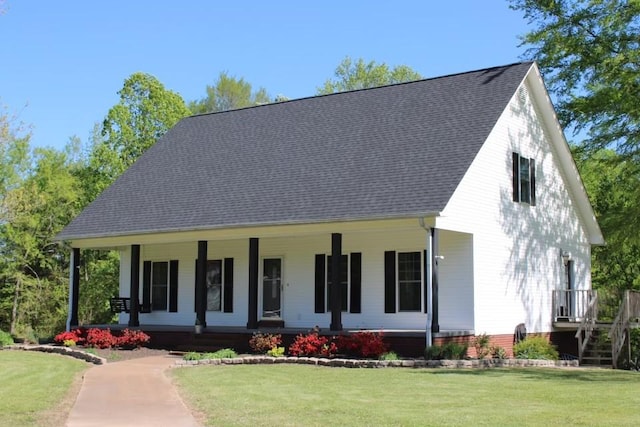 view of front of home with roof with shingles, a front yard, and covered porch