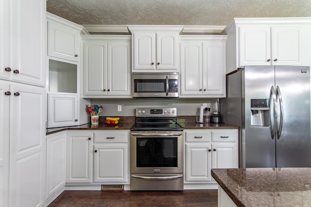 kitchen featuring dark stone counters, appliances with stainless steel finishes, a textured ceiling, and white cabinetry
