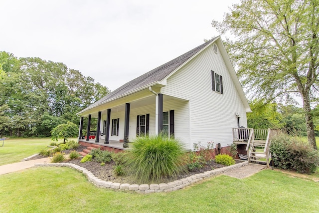view of side of property featuring a lawn, a porch, stairway, and roof with shingles