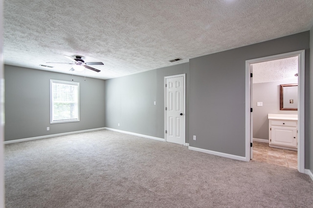 unfurnished room featuring a textured ceiling, ceiling fan, light carpet, baseboards, and visible vents